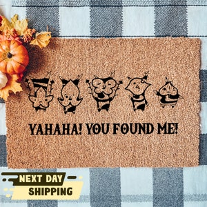 May include: A brown coir doormat with five black cartoon characters and the text "YAHAHA! YOU FOUND ME!"