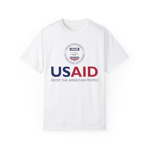 May include: White t-shirt with a blue and red USAID logo and the text "USAID From the American People".