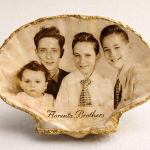 Puede incluir: Fotografía en tonos sepia de cuatro personas dentro de una concha marina con borde dorado. La imagen muestra a cuatro jóvenes. El texto "Florentz Brothers" está en la parte inferior.