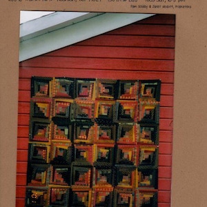 May include: A quilt shop advertisement featuring a quilt made of log cabin blocks in shades of black, brown, yellow, and red. The shop is called "The Buggy Barn" and is located in Reardan, WA.