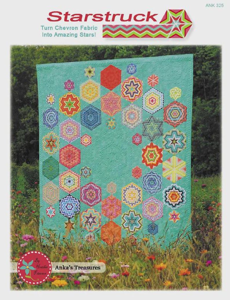 May include: A turquoise quilt with colorful star and hexagon patterns. The quilt features the text "Starstruck" and "Turn Chevron Fabric Into Amazing Stars!" The quilt is displayed outdoors in front of a field of flowers.
