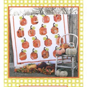May include: A quilt featuring a repeating pattern of orange and red fabric pumpkins with green stems on a white background. The text Sewn into the fabric... Pieces of our lives and Patch Work 58" x 70" is printed on the border of the image.