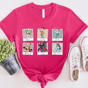 Puede incluir: Camiseta rosa con un gr&aacute;fico de seis personajes de Toy Story en marcos Polaroid. Los personajes son Buzz Lightyear, Woody, Jessie, Bullseye, Zurg y Bo Peep. El texto debajo de cada personaje dice "Buzz", "Woody", "Jessie", "Bullseye", "Zurg" y "Bo Peep".
