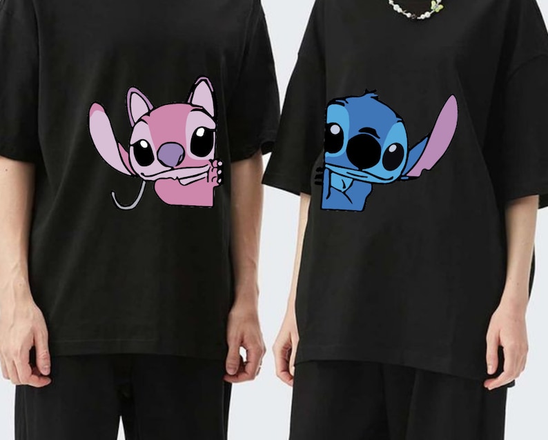 K&ouml;nnte beinhalten: Schwarze T-Shirts mit den Zeichentrickfiguren Angel und Stitch. Angel ist rosa und Stitch ist blau. Beide Charaktere sind teilweise auf den Shirts zu sehen. Die Shirts haben kurze &Auml;rmel und eine lockere Passform.