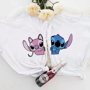 K&ouml;nnte beinhalten: Zwei wei&szlig;e T-Shirts mit Zeichentrickfiguren. Ein Shirt hat eine rosa Figur, das andere eine blaue Figur. Beide Figuren stammen aus derselben Zeichentrickserie. Die Shirts sind wahrscheinlich aus Baumwolle und f&uuml;r den Freizeitgebrauch geeignet.