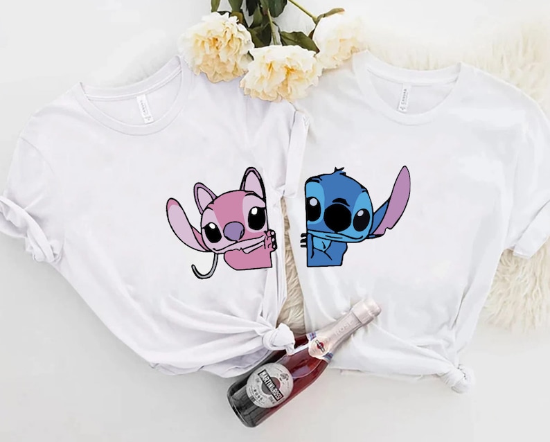 K&ouml;nnte beinhalten: Zwei wei&szlig;e T-Shirts mit Zeichentrickfiguren. Ein Shirt hat eine rosa Figur, das andere eine blaue Figur. Beide Figuren stammen aus derselben Zeichentrickserie. Die Shirts sind wahrscheinlich aus Baumwolle und f&uuml;r den Freizeitgebrauch geeignet.