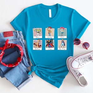 Puede incluir: Una camiseta azul turquesa con un gr&aacute;fico de seis personajes de Toy Story en marcos Polaroid. Los personajes son Buzz Lightyear, Woody, Jessie, Bullseye, Zurg y Bo Peep. El texto debajo de cada marco identifica al personaje.