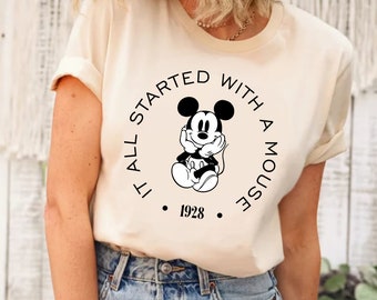 May include: A white t-shirt with a black graphic of Mickey Mouse. The graphic says "It all started with a mouse. 1928."
