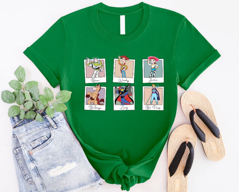 Puede incluir: Camiseta verde con un gr&aacute;fico de seis personajes de Toy Story en marcos Polaroid. Los personajes son Buzz Lightyear, Woody, Jessie, Bullseye, Zurg y Bo Peep. El texto debajo de cada personaje dice "Buzz", "Woody", "Jessie", "Bullseye", "Zurg" y "Bo Peep".