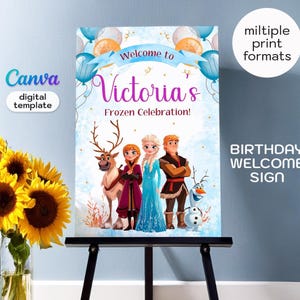 May include: A rectangular birthday welcome sign featuring the text Welcome to Victoria's Frozen Celebration! with illustrations of characters from the movie Frozen, including a reindeer, two people, and a snowman, decorated with blue balloons.