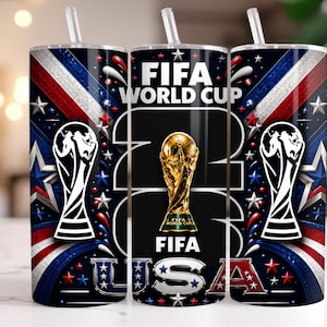 May include: A cylindrical tumbler with a clear straw featuring a dark blue, red, and white design. The graphic includes the text FIFA WORLD CUP 2026 USA, a gold trophy illustration, and white silhouettes of the FIFA World Cup trophy.