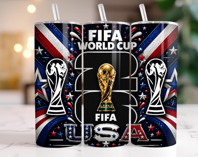 May include: A cylindrical tumbler with a clear straw featuring a dark blue, red, and white design. The graphic includes the text FIFA WORLD CUP 2026 USA, a gold trophy illustration, and white silhouettes of the FIFA World Cup trophy.