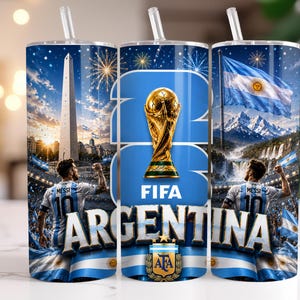 May include: A cylindrical tumbler with a straw featuring a graphic design of the FIFA World Cup trophy, the text "ARGENTINA" and "FIFA", the Obelisco de Buenos Aires, the Argentine flag, and a football player wearing a jersey with "MESSI 10".