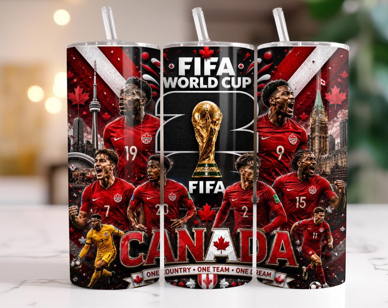 May include: A cylindrical tumbler with a straw featuring a FIFA World Cup graphic, the text "CANADA" and "ONE COUNTRY ONE TEAM ONE DREAM," and multiple football players in red jerseys, the CN Tower, and the FIFA World Cup trophy on a dark background.