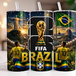May include: A cylindrical tumbler with a clear straw featuring a Brazil football theme. The design includes the Christ the Redeemer statue, the FIFA World Cup trophy, the Brazilian flag, and a football player in a yellow jersey with the number 10.