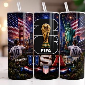May include: A cylindrical tumbler with a straw featuring a 2026 FIFA World Cup theme. The design includes the USA flag, the Golden Gate Bridge, the Statue of Liberty, the White House, a soccer player in a USA jersey, and the text 2026 FIFA USA.