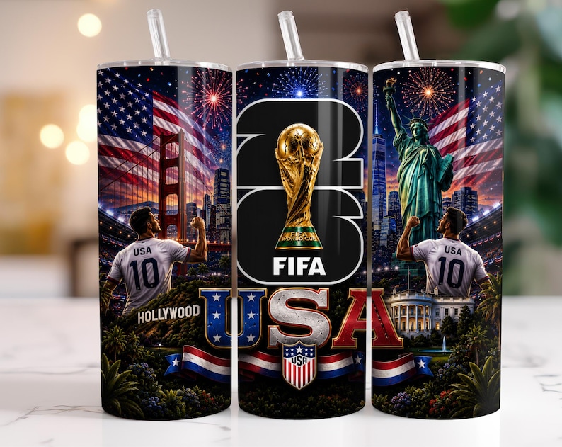 May include: A cylindrical tumbler with a straw featuring a 2026 FIFA World Cup theme. The design includes the USA flag, the Golden Gate Bridge, the Statue of Liberty, the White House, a soccer player in a USA jersey, and the text 2026 FIFA USA.
