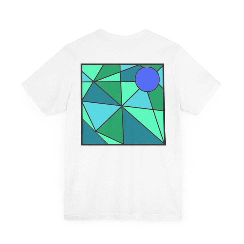 K&ouml;nnte beinhalten: Wei&szlig;es T-Shirt mit einem geometrischen Design in Gr&uuml;n-, Blau- und T&uuml;rkist&ouml;nen. Das Design enth&auml;lt einen Kreis in der oberen rechten Ecke.
