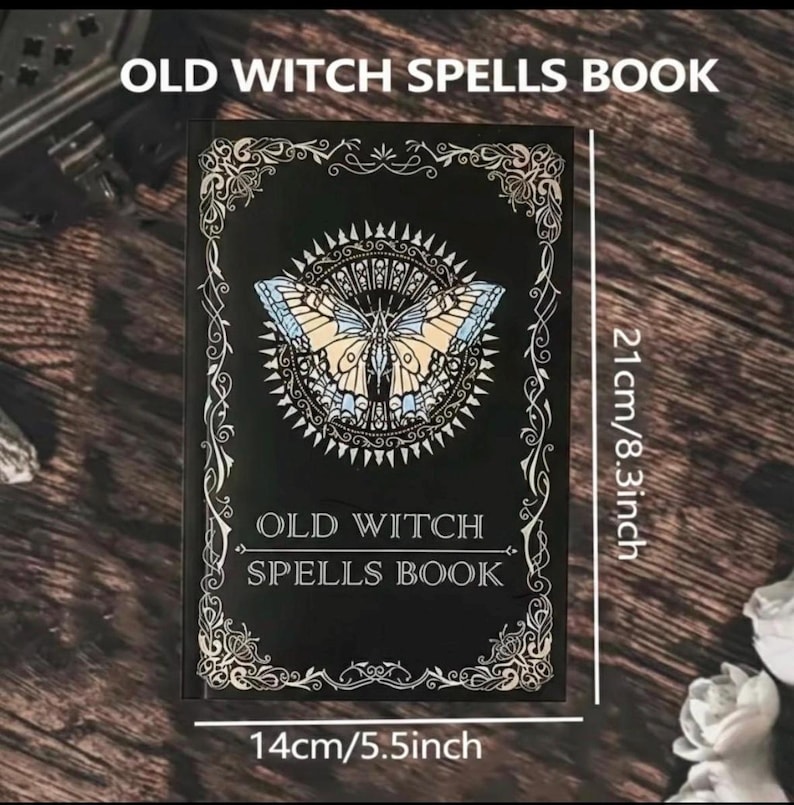 以下が含まれることがあります： 「OLD WITCH SPELLS BOOK」と書かれた黒い本。蝶のデザインが施されています。本の幅は14cm、高さは21cmです。蝶は青、タン、白のディテールがあります。本の縁には装飾的なスクロールワークがあります。