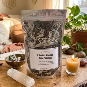 May include: A clear, resealable bag filled with dried herbs, labeled "7 Hierbas Amargas Baño Espiritual." A selenite crystal, a small brass bowl with herbs, and a lit candle sit on a wooden surface. A potted plant is in the background.
