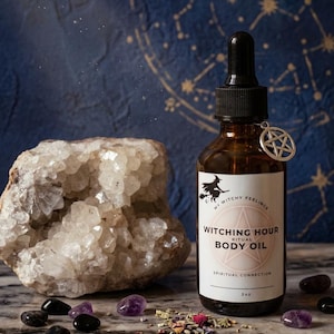 Op de afbeelding: Een bruine glazen fles Witching Hour Ritual Body Oil met een zwarte druppelaar en een zilveren pentagrambedel. Het etiket toont een heksensilhouet. Amethist en zwarte stenen, een grote kristal en gedroogde kruiden zijn verspreid.