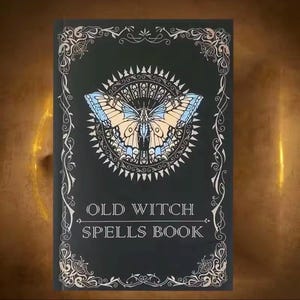 以下が含まれることがあります： 「OLD WITCH SPELLS BOOK」のテキストが入った黒い本の表紙。青とベージュの蝶のイラストが特徴で、装飾的なサンバーストのデザインで囲まれています。装飾的な銀色のスクロールワークが縁を縁取っています。