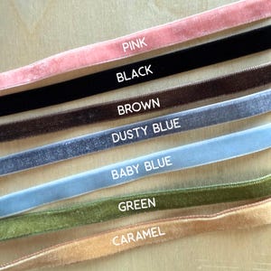 Puede incluir: Siete tiras paralelas de cinta de terciopelo en rosa, negro, marr&oacute;n, azul polvoriento, azul beb&eacute;, verde y caramelo. Cada cinta est&aacute; etiquetada con el nombre de su color en texto blanco, dispuestas verticalmente de arriba a abajo.