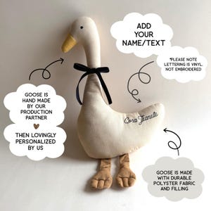 Puede incluir: Un juguete de peluche con forma de ganso de color crema, con pico amarillo y patas marrones. El ganso lleva un lazo negro atado al cuello. El nombre Cora Jeanette est&aacute; impreso en cursiva negra en el lateral. Burbujas de texto indican detalles.