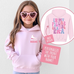 以下が含まれることがあります： ピンクのフード付きスウェットシャツ。前面には白いスケートのグラフィックと「REESE」の文字がプリントされています。背面には、カラフルなレトロなフォントで「IN MY FIGURE SKATING ERA」の文字がプリントされています。