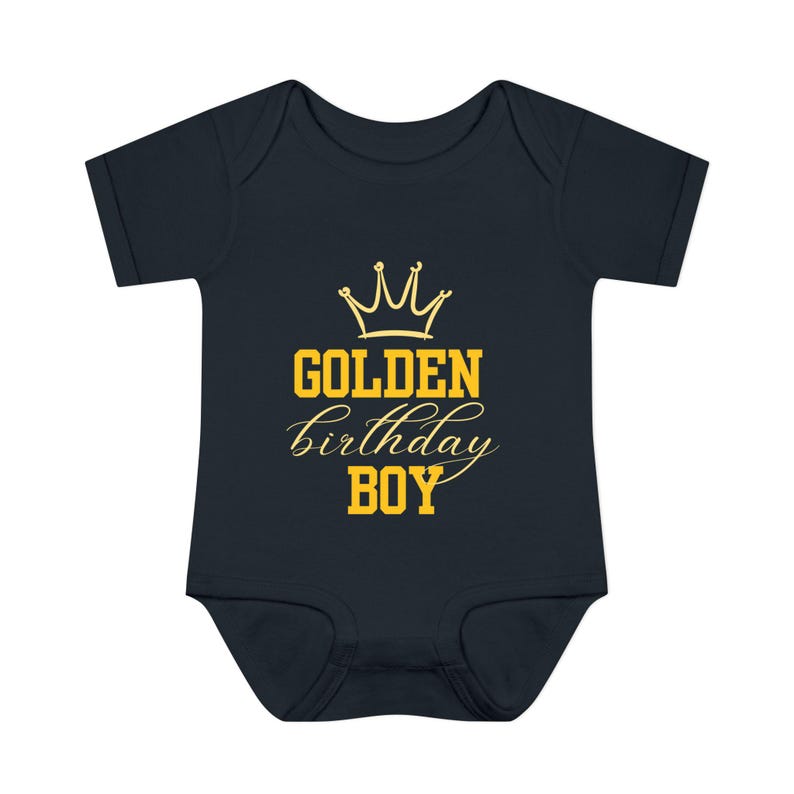 May include: A dark blue baby onesie with a gold crown and the text "GOLDEN birthday BOY".