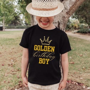 May include: A black t-shirt with a gold crown and the text "GOLDEN birthday BOY" printed on it.