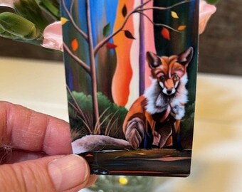 May include: A colorful illustration of a fox sitting in a forest setting. The fox is orange and white with a bushy tail. The background is a vibrant mix of blue, green, orange, and red.