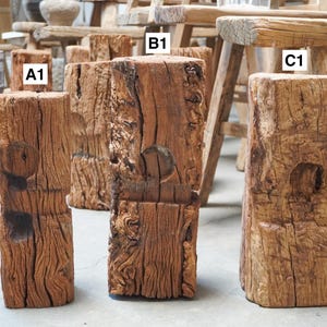 K&ouml;nnte beinhalten: Drei verwitterte, rechteckige Holzbl&ouml;cke mit den Beschriftungen A1, B1 und C1. Jeder Block weist eine raue, strukturierte Oberfl&auml;che mit tiefer Maserung und einer kreisf&ouml;rmigen Vertiefung auf der Vorderseite auf. Das Holz ist mittelbraun mit sichtbaren Rissen.