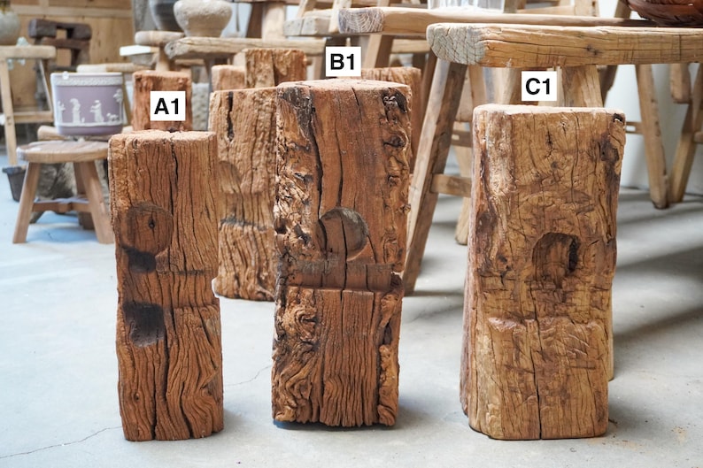 K&ouml;nnte beinhalten: Drei verwitterte, rechteckige Holzbl&ouml;cke mit den Beschriftungen A1, B1 und C1. Jeder Block weist eine raue, strukturierte Oberfl&auml;che mit tiefer Maserung und einer kreisf&ouml;rmigen Vertiefung auf der Vorderseite auf. Das Holz ist mittelbraun mit sichtbaren Rissen.