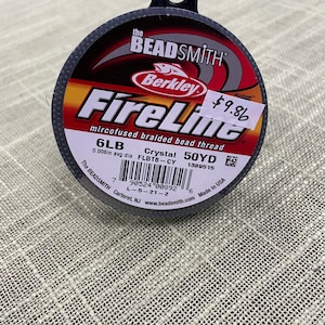 May include: A spool of 6lb FireLine Crystal bead thread, a microfused braided bead thread, by Berkley, The Beadsmith. The spool is 50 yards and has a 0.006in average diameter. The label is black, white, and red with the text "FireLine" in a large, bold, red font.