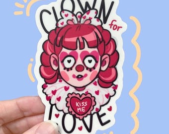 May include: A sticker featuring a cartoon clown with pink hair, makeup, and a heart-shaped collar. The text "CLOWN for LOVE" is written around the clown's head. The clown has a heart that says "KISS ME".