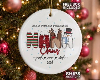 May include: A round white ceramic Christmas ornament featuring the text NANA CLAUS in decorative letters. The letters are styled with red and green stripes, a brick pattern, a reindeer, and a snowman. Includes the names Joseph, Mary, and Steph.