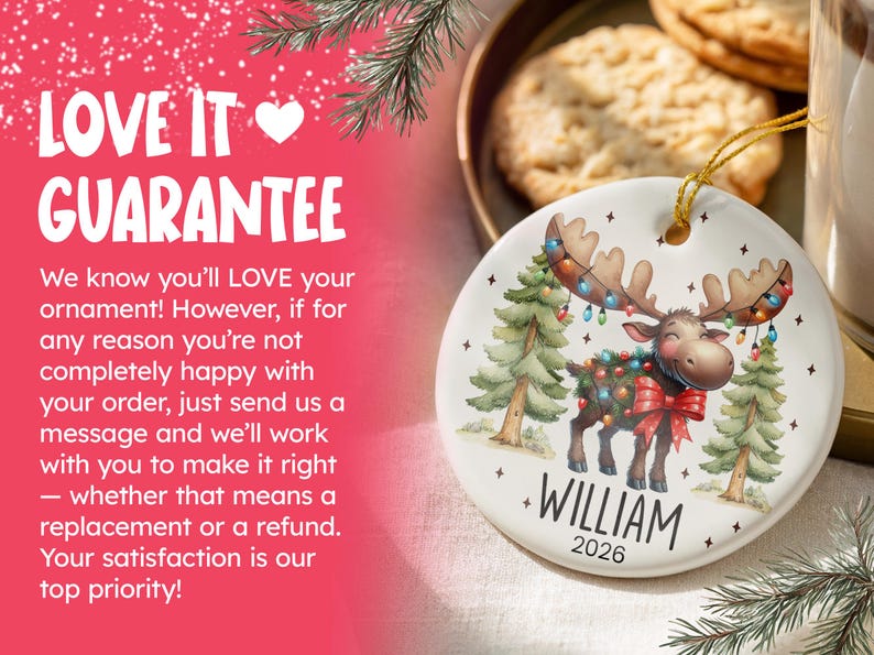 Op de afbeelding: Een rond wit keramieken ornament met een cartoon-eland met een gewei versierd met kleurrijke kerstverlichting, staand tussen twee dennenbomen. De naam WILLIAM en het jaartal 2026 staan in zwarte letters onder de illustratie van de eland.