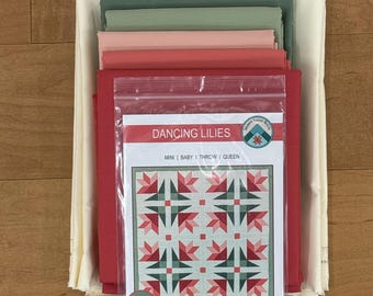 May include: A quilting kit with fabric in shades of red, pink, and green, along with a pattern titled "Dancing Lilies." The kit includes fabric for mini, baby, throw, and queen-sized quilts. The skill level is confident beginner.