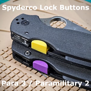 May include: Two Spyderco pocket knives with different colored lock buttons. The top knife has a yellow lock button and the bottom knife has a purple lock button. The knives are labeled "Para 3 / Paramilitary 2".