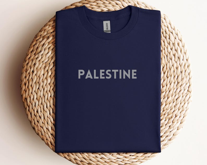 May include: A navy blue t-shirt with the word "PALESTINE" printed in white on the front.