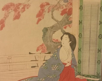 May include: Japanese woodblock print featuring a woman in a blue floral robe and red garment, seated near a tree with red leaves. A small table and text are visible. The artwork has a traditional aesthetic.