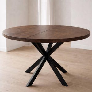 May include: A round wooden dining table with a dark brown finish. The table has a black metal base with an X-shaped design. The table is approximately 48 inches in diameter.