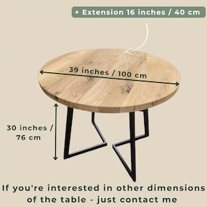 May include: A round wooden table with a natural grain finish and black metal legs. The table has a diameter of 39 inches, a height of 30 inches, and an optional extension of 16 inches. Text on the image reads: + Extension 16 inches / 40 cm.