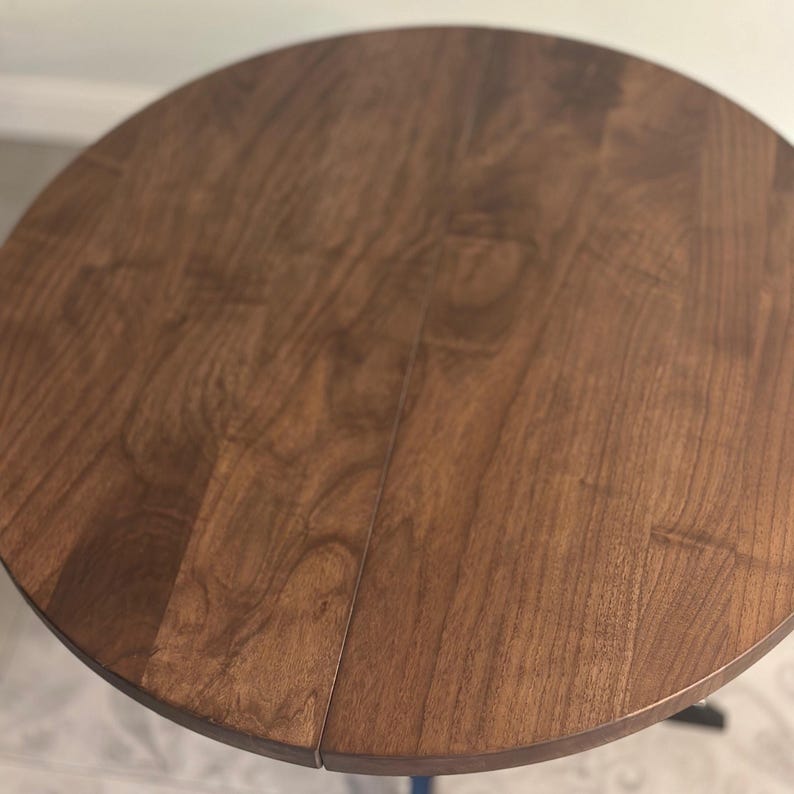 Peut inclure: Une table ronde en bois avec une finition marron fonc&eacute;. Le plateau de table pr&eacute;sente un motif de grain de bois visible. Il s'agit probablement d'une petite table d'appoint, d'environ 76 cm de diam&egrave;tre.