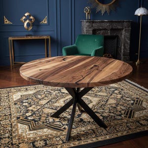 May include: A round dining table featuring a natural wood grain top with visible dark knots and swirling patterns, supported by a black metal base with four intersecting legs that form an X-shape at the center point beneath the tabletop surface.