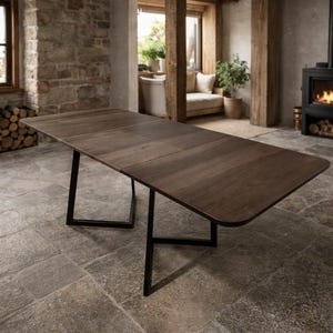 Op de afbeelding: Een rechthoekige eettafel van donkerbruin hout. De tafel heeft een modern design met zwarte metalen poten. De tafel is ongeveer 183 cm lang en 91 cm breed.