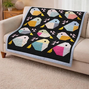 Könnte beinhalten: Eine Steppdecke mit einem sich wiederholenden Muster aus stilisierten Vögeln in verschiedenen Pastellfarben wie Rosa, Blau, Gelb und Grün. Die Vögel sind vor einem einfarbigen schwarzen Hintergrund mit kleinen geometrischen Akzenten platziert.