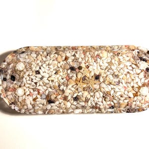 Handcrafted resin tray featuring assorted mini shells, creating a one-of-a-kind piece.