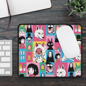 May include: A rectangular mousepad featuring a colorful grid pattern with various anime characters. The design includes characters in pink, yellow, blue, and black squares. A white computer mouse rests on the pad.